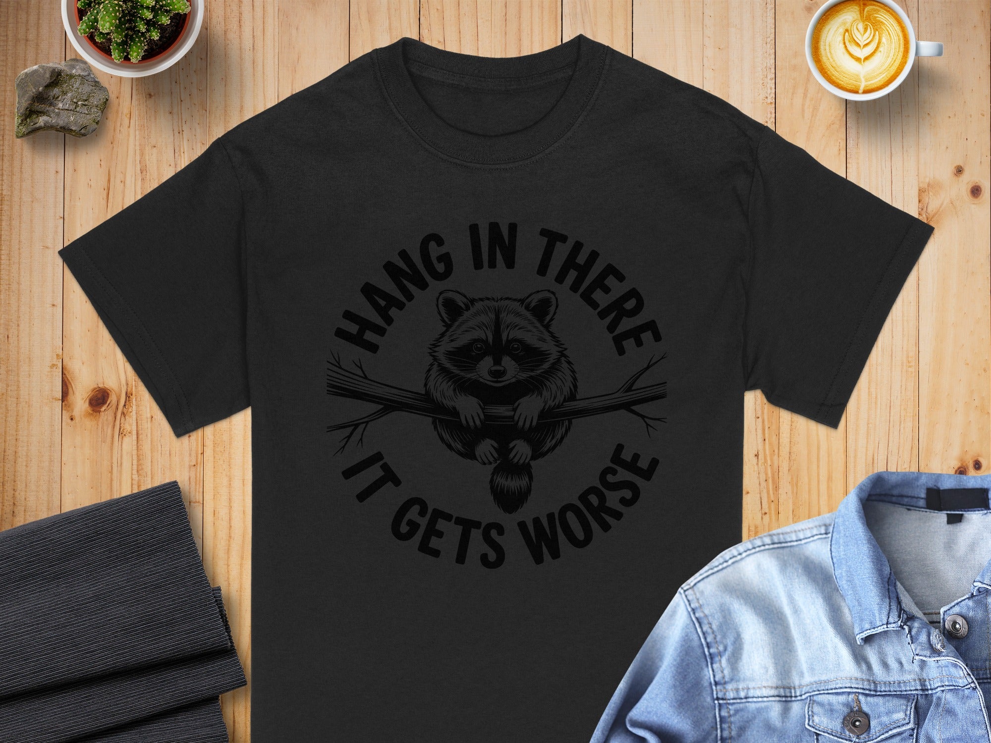 Black t-shirt with raccoon graphic and text "Hang in there it gets worse."