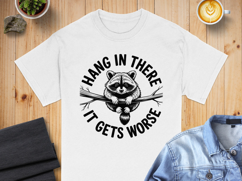 White t-shirt with a raccoon illustration and "Hang in there, it gets worse" text.